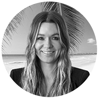 Smiling woman with long hair in front of a beach and palm tree background.